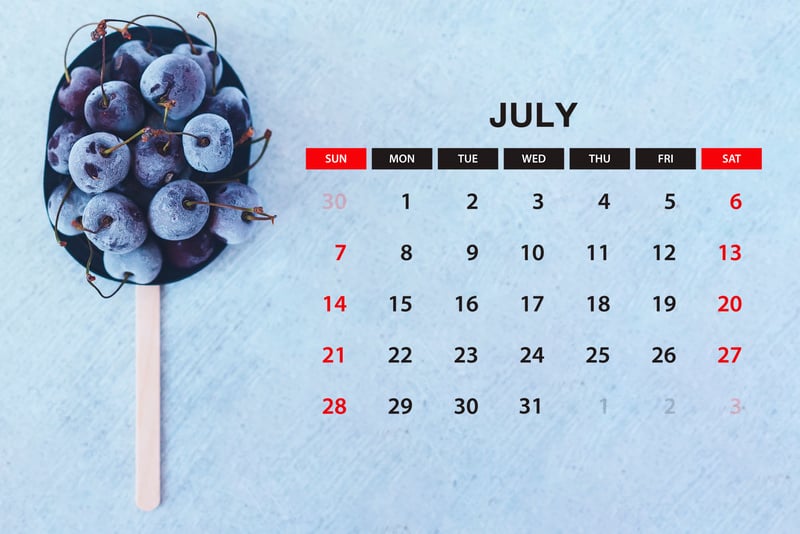 July calendar. Stack of frozen sweet cherries with July month calendar. Summer